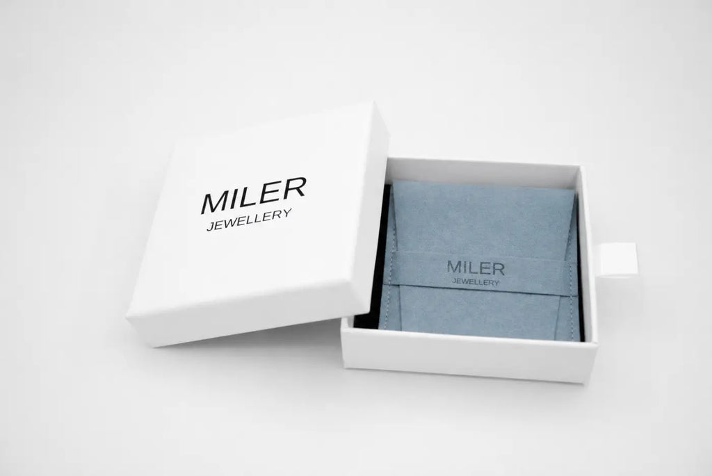 A light blue velvet jewelry pouch with miler jewellery printed in black inside a white box for polished yellow gold hoops with smartlock fastening